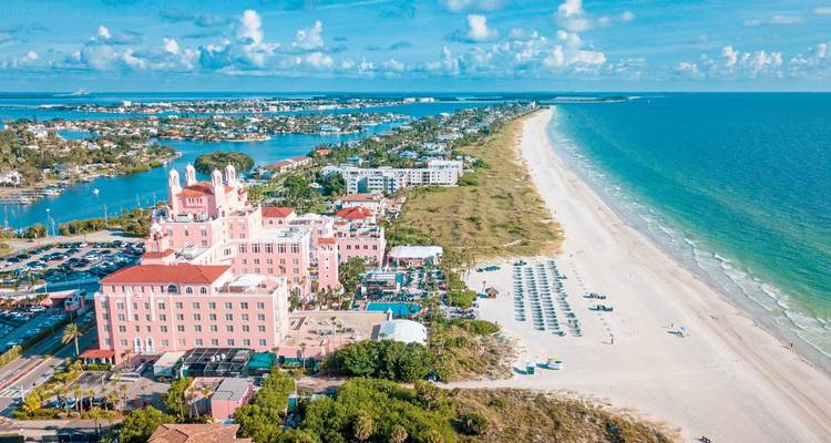 Vista aérea de un resort frente al mar con una playa de arena y aguas azules.