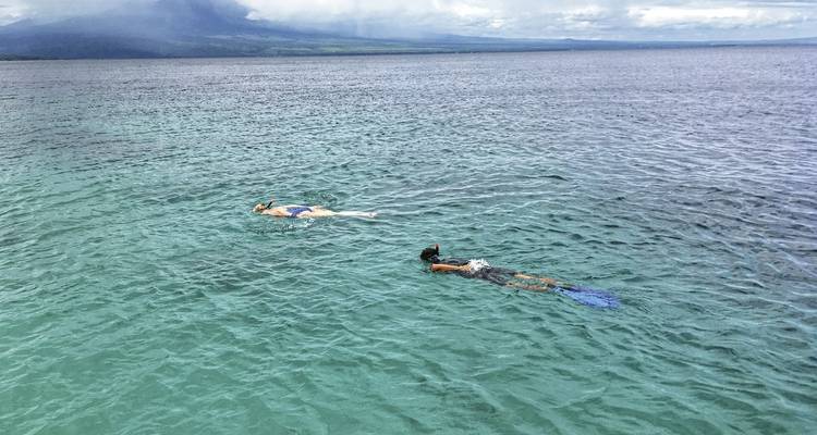 Dos personas haciendo snorkel en aguas azules cristalinas.