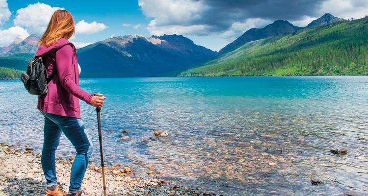 Wandelaar die een kristalhelder meer met bergen bewondert.