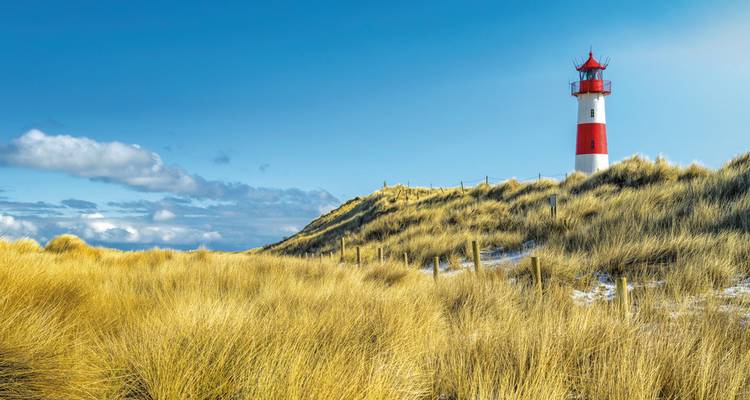 Sylts ikonischer Leuchtturm umgeben von Sanddünen.