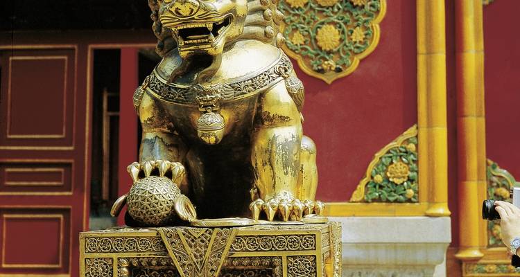 Goldene Löwenstatue vor einem Tempel.