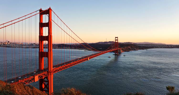 Golden Gate Bridge, die sich bei Sonnenuntergang über das Wasser spannt.