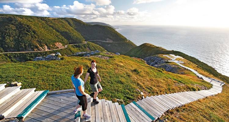 Deux personnes sur une promenade en bois surplombant des falaises océaniques.