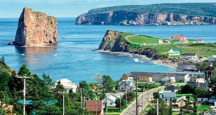 Ville côtière avec route menant à une grande formation rocheuse dans l'océan.