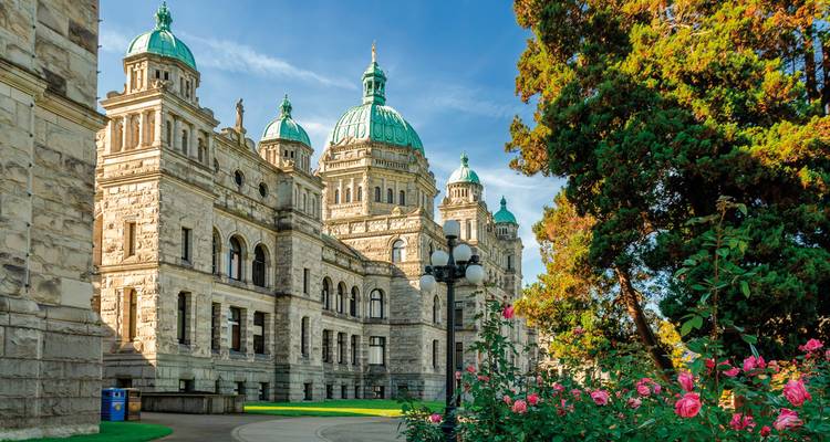 A historical building with green domes surrounded by gardens.