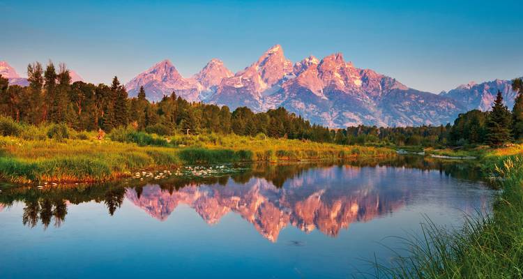 Reflejo de montañas en un lago sereno al atardecer.
