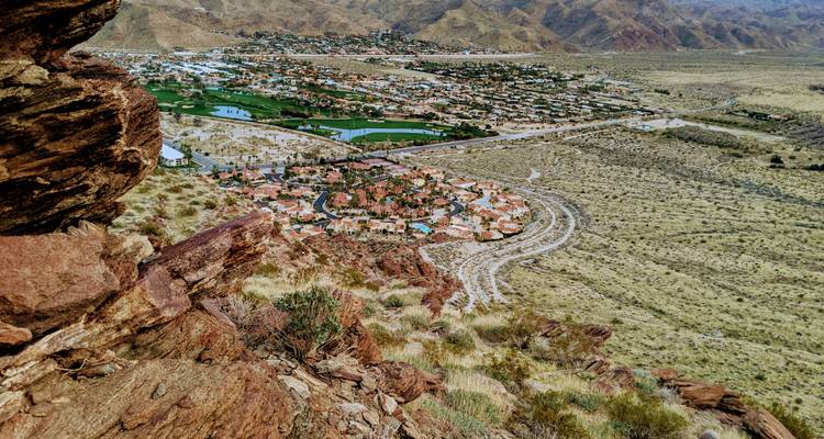 Paisaje de un área desértica con vegetación y casas distantes, probablemente en Palm Springs.