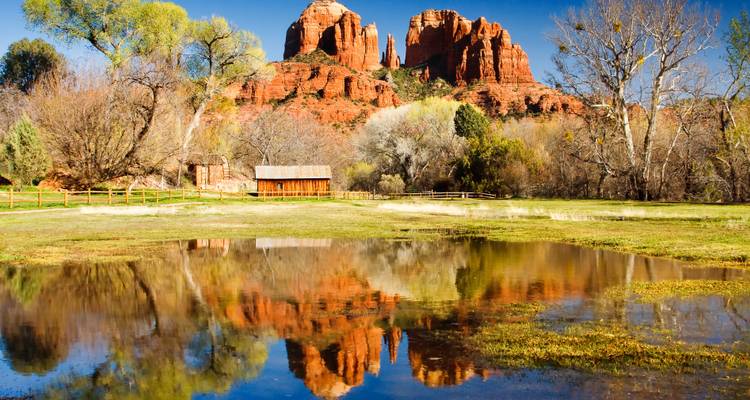 Vista serena de Cathedral Rock reflejada en el agua con árboles circundantes en Sedona.