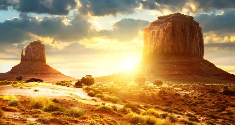 Lever de soleil sur Monument Valley avec une lumière dorée.