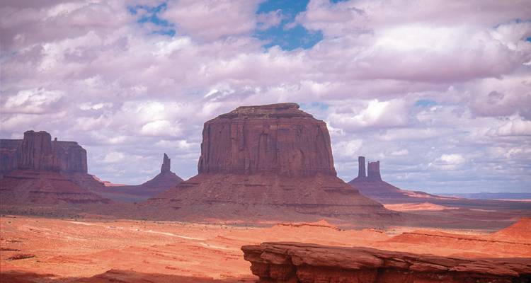 Les célèbres buttes de Monument Valley sous un ciel partiellement nuageux.
