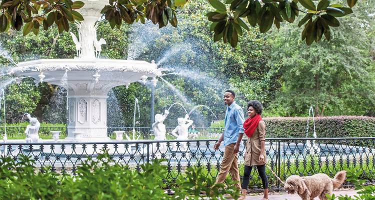 Couple se promenant près d'une fontaine dans un parc.