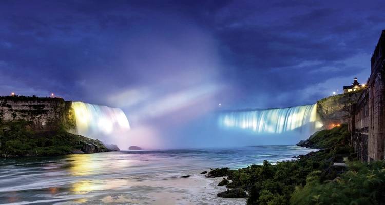 Dramatisch beleuchteter Wasserfall bei Nacht mit leuchtenden Farben.