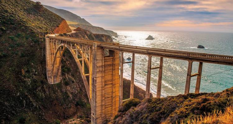 Une autoroute côtière avec un grand pont arqué au-dessus de l'océan.