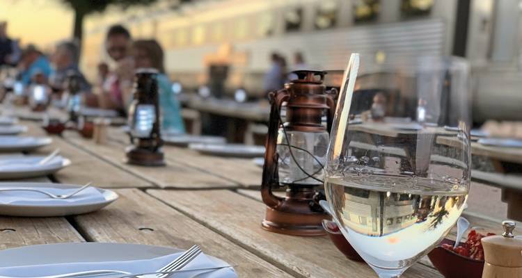 Essensaufbau neben einem Zug mit Personen im Hintergrund.