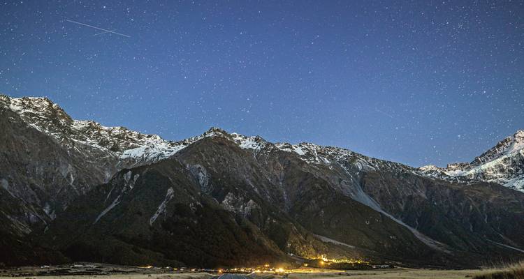Cielo estrellado sobre cordillera montañosa de noche.