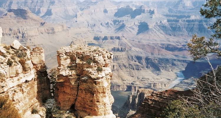 Grand Canyon avec des formations rocheuses stratifiées et une rivière qui le traverse.