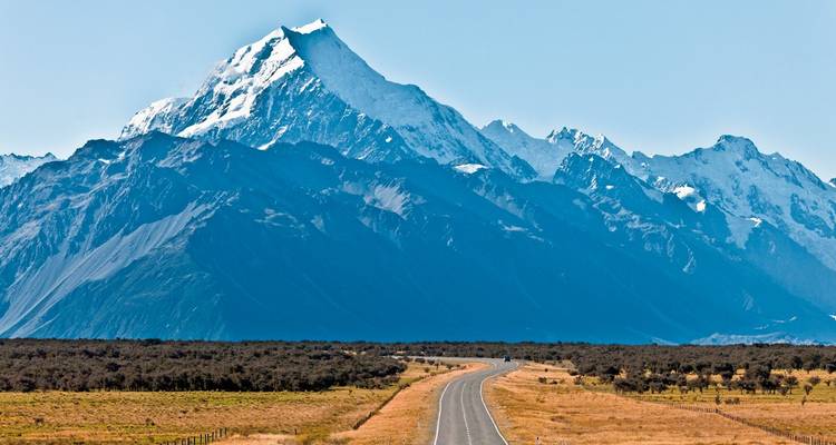 Route menant vers d'imposantes montagnes enneigées.