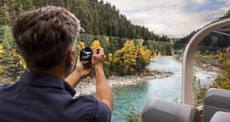 Passagier die een rivier fotografeert vanuit een schilderachtige trein.