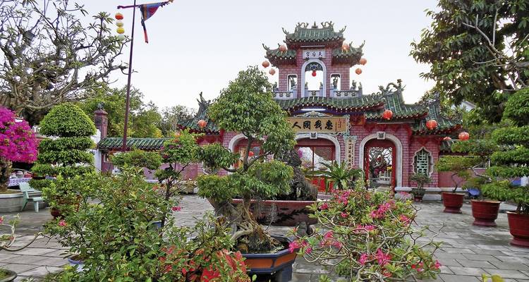 Traditionele tempel omgeven door levendige planten en bomen.