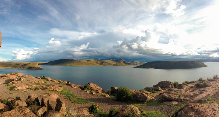 Panoramablick auf einen See, umgeben von hügeligem Gelände.