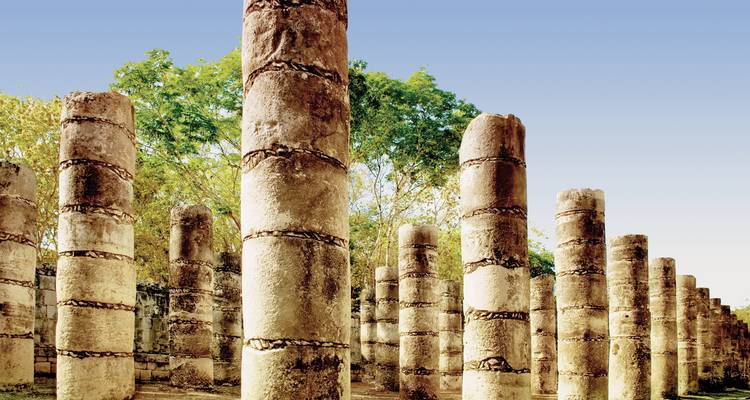 Talloze oude stenen zuilen die onder een heldere hemel staan.