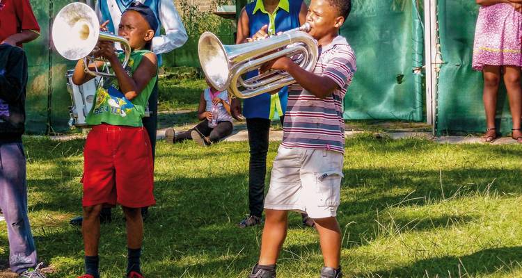 Kinder, die draußen Blechblasinstrumente spielen.