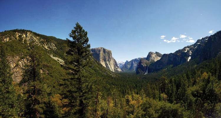 Panoramablick auf ein Tal mit Wäldern und Bergen.