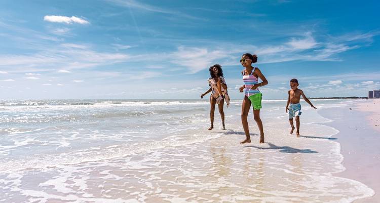 Family playing at the beach with gentle waves in the background.