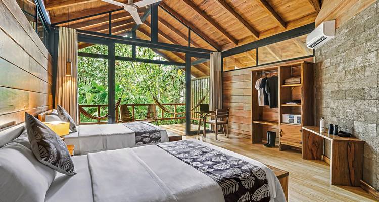 Une chambre spacieuse et bien éclairée avec deux lits, une vue sur la jungle et une décoration en bois.