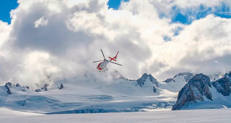 Hubschrauber fliegt über schneebedeckte Berge