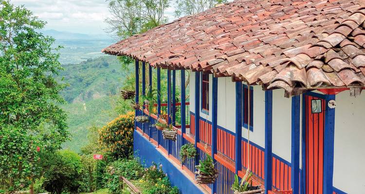 Traditionelles Haus mit bunten blauen und roten Verzierungen mit Blick auf eine grüne Landschaft.