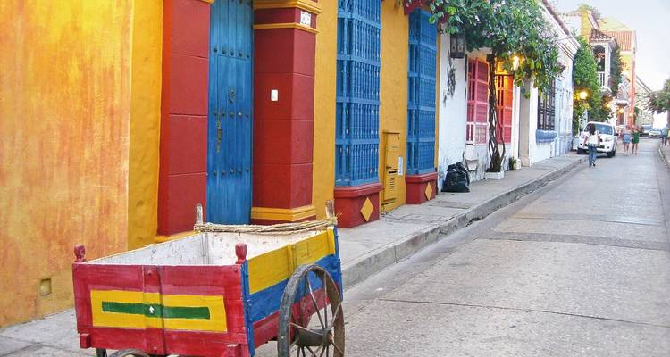 Bunte Straße mit einem rustikalen Wagen und lebendigen Gebäuden.
