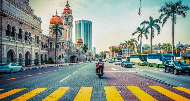 Rue de ville avec circulation et bâtiments historiques, avec une tour d'horloge.