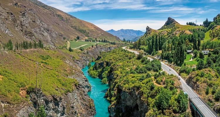 River flowing through a scenic valley with mountains in the background.