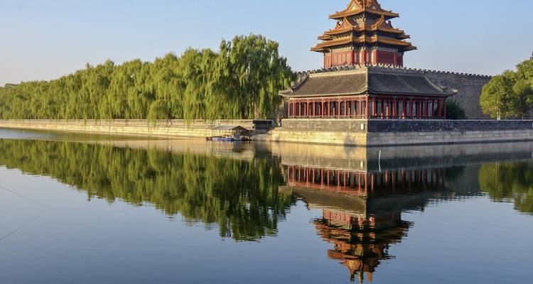 Bâtiment chinois historique avec reflet d'eau et verdure.