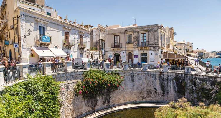 Pueblo histórico con gente caminando sobre un puente.