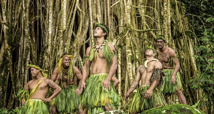 Groep mannen in traditionele kledij staand in een bos.