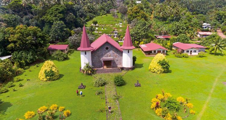 Aerial view of a church and cemetery surrounded by lush greenery.