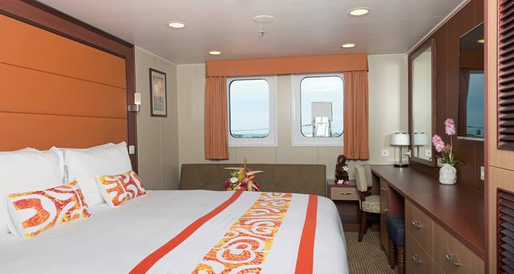Interior view of a ship cabin with a bed and windows.