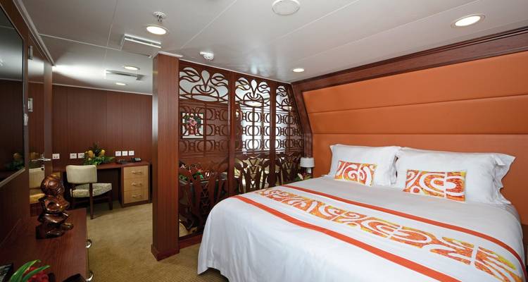 Interior of a cabin with a bed and decorative wood paneling.