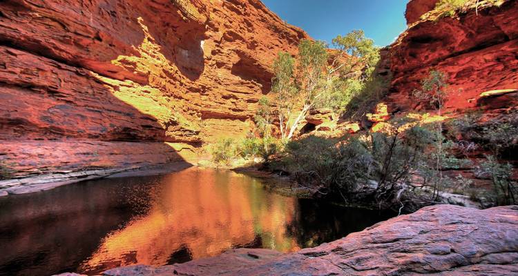 A serene gorge with reflections in a still pool.
