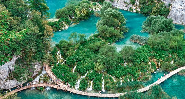 Plitvicer Seen mit Holzstegen, die über klares blaues Wasser und üppige Vegetation führen.