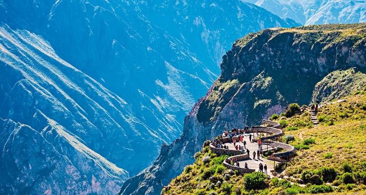 Touristen, die eine dramatische Berglandschaft von einem Aussichtspunkt aus betrachten.