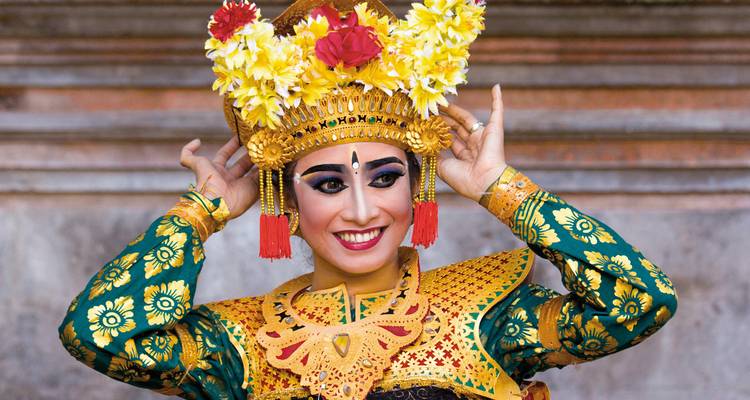 Persoon gekleed in traditionele Balinese kleding met een bloementooi.
