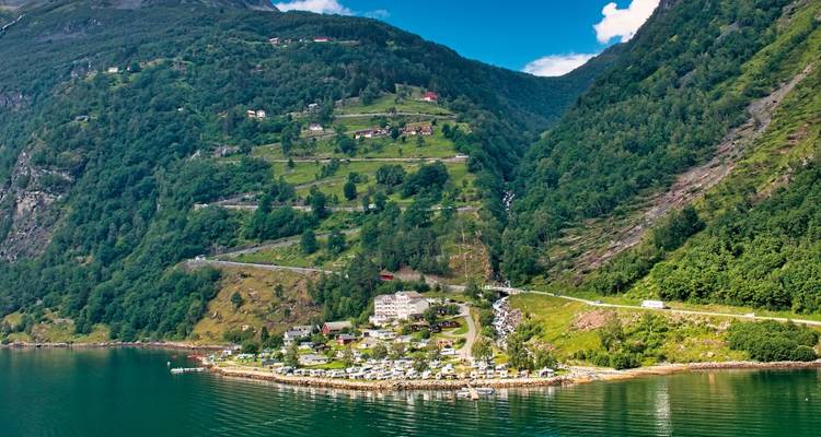 A village by a fjord with surrounding lush greenery.