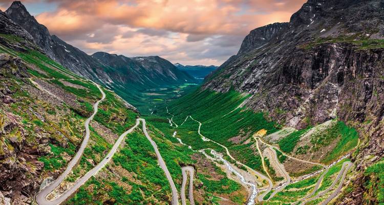 Winding mountain road with dramatic cliffs and lush greenery.