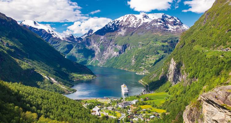 Majestic fjord surrounded by mountains and green landscape with a cruise ship.