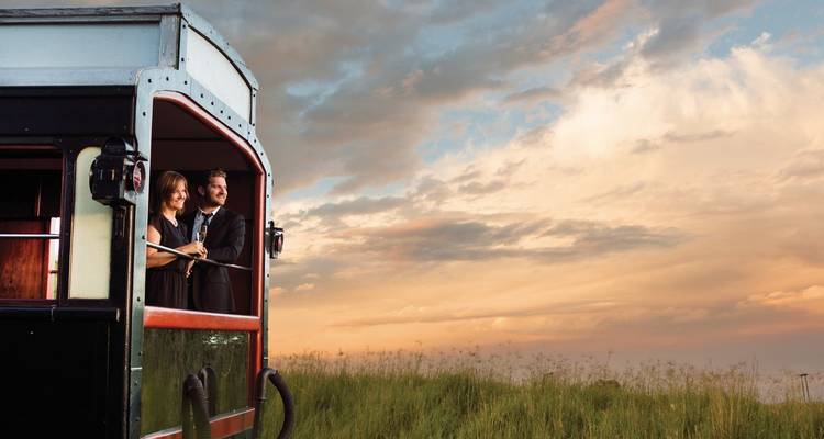 Ein Paar genießt die Aussicht vom letzten Waggon eines Zuges in der Abenddämmerung.