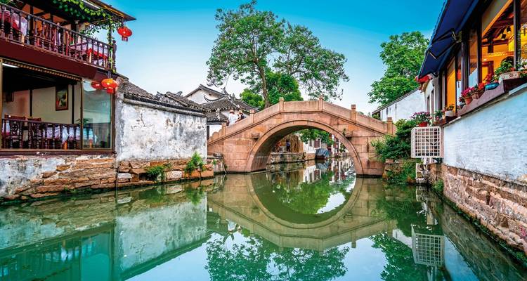 Traditional stone bridge over a calm canal with historical buildings.