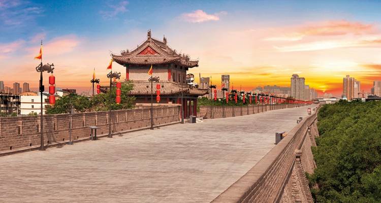 Ancient city wall at sunset with traditional architecture.